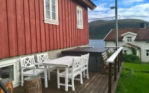 Outside patio of Budeia Lodge with hot tub and white table during summer in Kvaløya, Arctic Norway