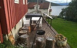 Outside patio of Budeia Lodge during summer with hot tube, table, and outdoor grill in Kvaløya, Arctic Norway