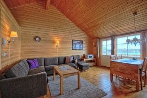 Living room with sofas and kitchen table of Eliassen Rorbuer wood cabin in Hamnøy, Lofoten Islands, Norway