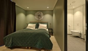 Green and white double bed and bathroom in Lyngen Experience Lodge, Norway