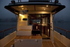 Lyngen Experience private boat back deck at night with view of hot tub, stairs, and interior