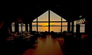 Sunset view from interior Lyngen Experience Lodge living room full-length window