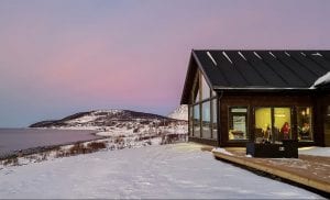 Lyngen Experience Lodge left side exterior in winter in front of pink and blue sky
