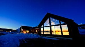 Lyngen Experience Lodge exterior at night with full-length window view of lit up sauna and spa area inside in Lyngen, Arctic Norway
