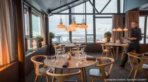 Set tables and blurry waitress with daytime window view of mountains in restaurant at Funken Lodge in Svalbard, Arctic Norway