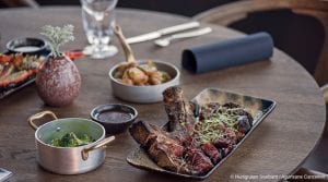 Meat dish and broccoli dish in focus on table of restaurant at Funken Lodge, Svalbard