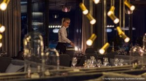Blonde girl with glasses serving water at empty table full of glasses in restaurant of Funken Lodge in Svalbard, Arctic Norway