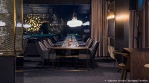 Empty long dining table with wine glasses and grey chairs in restaurant of Funken Lodge in Svalbard, Arctic Norway