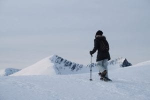 Guest snowshoeing in snowy mountains white sky backdrop