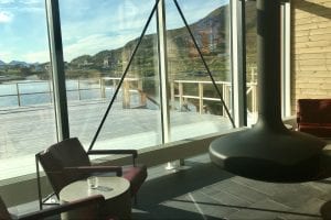 Sommaroy Arctic Hotel interior suspended electric fireplace with window view of outdoor boardwalk