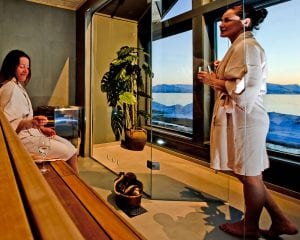 Two women in bathrobes with wine glasses in modern sauna of Lyngen Experience Lodge Spa in Lyngen, Arctic Norway