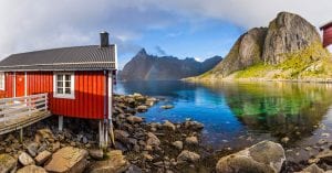 Elissen Rorbuer red cabin near a lake with mountain fjords lofoten and a rainbow