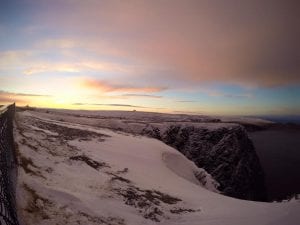North Cape covered in snow with sunset sun setting and snow covered with sea of water