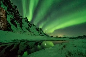 Northern Lights Aurora Borealis with snow covered mountains and lake