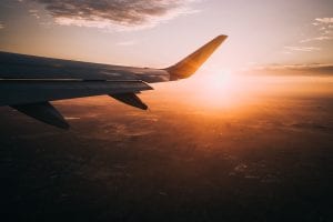 Aeroplane Airplane Plane window view of the wing in the sky with sun golden hour and clouds