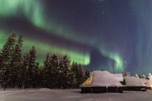 Northern Lights Aurora Borealis with snow covered Aurora Cabins
